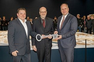 Bild von drei Personen, die einen symbolischen Schlüssel halten