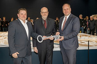 Image of three people holding a symbolic key