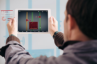 Foto von einer Person, die man von hinten sieht und ein Tablet in den Händen hoch hält