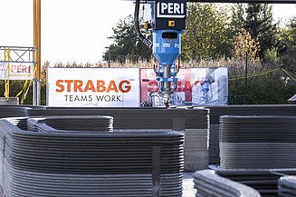 Foto von einem 3D-Drucker, der Trockenmörtel schichtweise aufträgt, wodurch Wände entstehen.