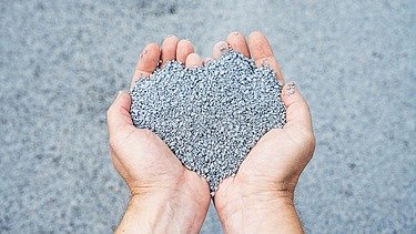 The picture shows two hands holding a pile of grey-blue balls