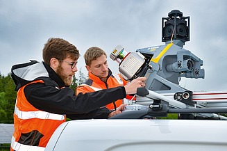 Foto von zwei Personen in Schutzwesten mit einem mobilen Laserscanner