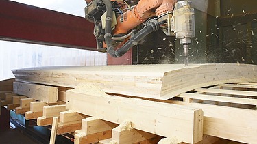 Foto beim bearbeiten von Holz mit einer Industriebohrmaschine.  