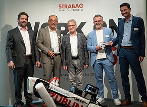 Foto von mehreren Personen, die hinter einen Roboterhund stehen. 