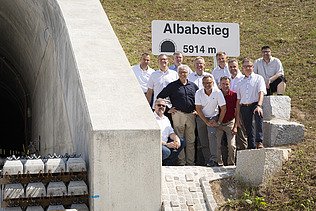 Foto von freundlich schauenden Männern, die neben einem Tunell stehen. 