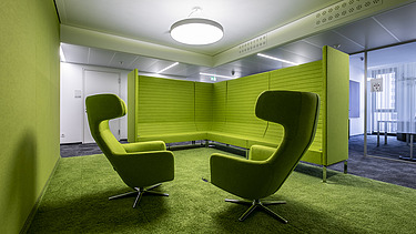 Foto von zwei grünen Sesseln in einem grünen verkleidetet Raum.