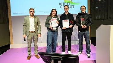 Foto von vier Personen auf einer Bühne. 