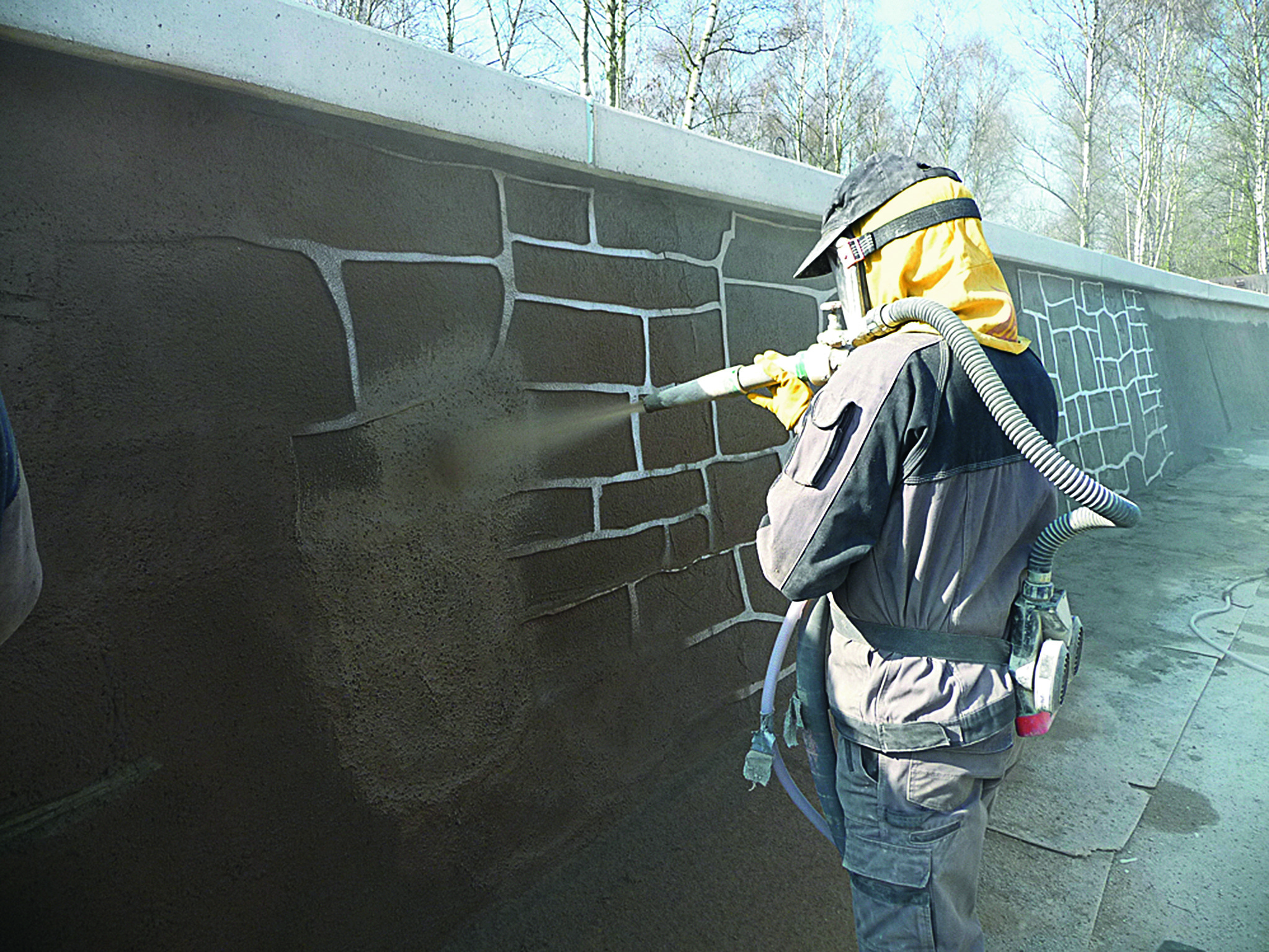  Foto von einer Person, die eine Wand mit brauner Farbe besprüht.