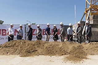 Foto von mehreren Personen die mit einem Sparten Erde schaufeln.   