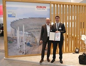 Zwei Männer mit Urkunde vorm ZÜBLIN-Forschungspreis Banner. 