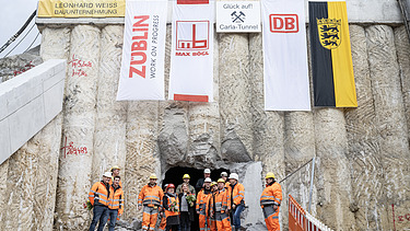 Foto von mehren Personen in Schutzausrüstung beim feierlichen Durchschlag zur Wendlinger Kurve.