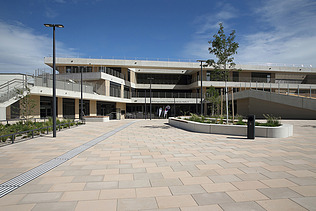 Foto von einem modernen Gebäude bei blauem Himmel, davor ein gepflasterter Platz
