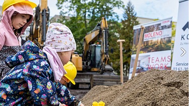 Foto von Kindern die eine Schaufel in die Erde stecken. 