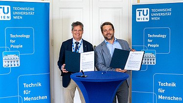 Photo of four people standing at a bar table and two blue roll-ups behind them