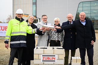 Foto von mehreren Personen, die eine Röhre halten zum Richtfest.  