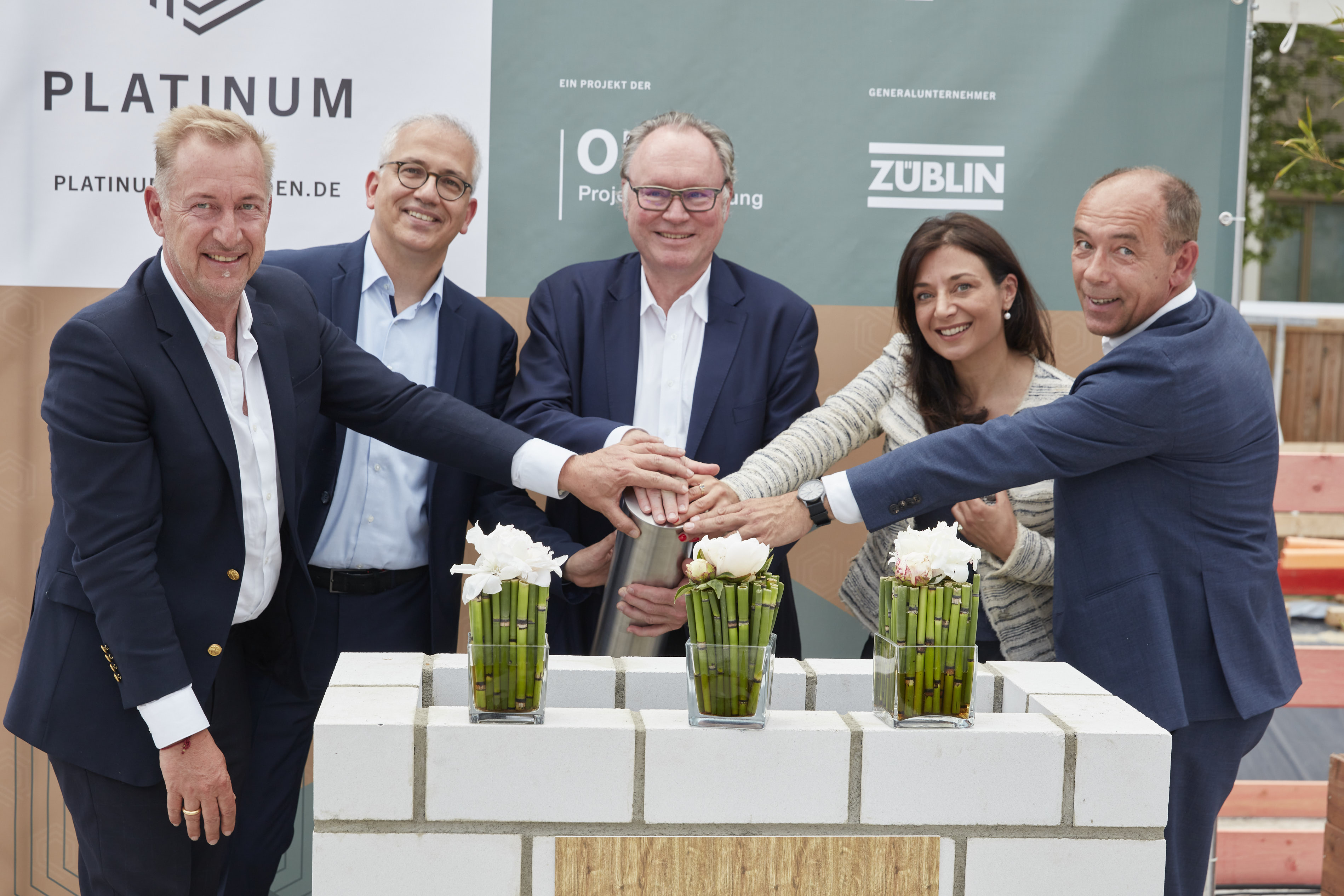 Foto von mehreren Personen, die ihre auf eine Röhre legen zur Grundsteinlegung.   