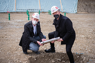 Foto von zwei Männern die eine Zeitkapsel vergraben.  