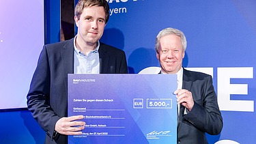 Foto von zwei lächelnden Personen die den Innovationspreis 2022 halten. 