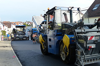 Foto von mehreren Straßenbaumaschinen auf einer frisch asphaltierten Straße