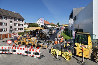 Foto einer Straßenbaustelle im Vordergrund eine weiß-rote Absperrung