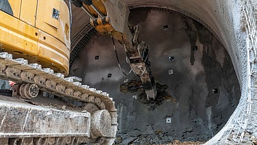 Nahaufnahme von einem Bagger der einen Tunnel gräbt.  