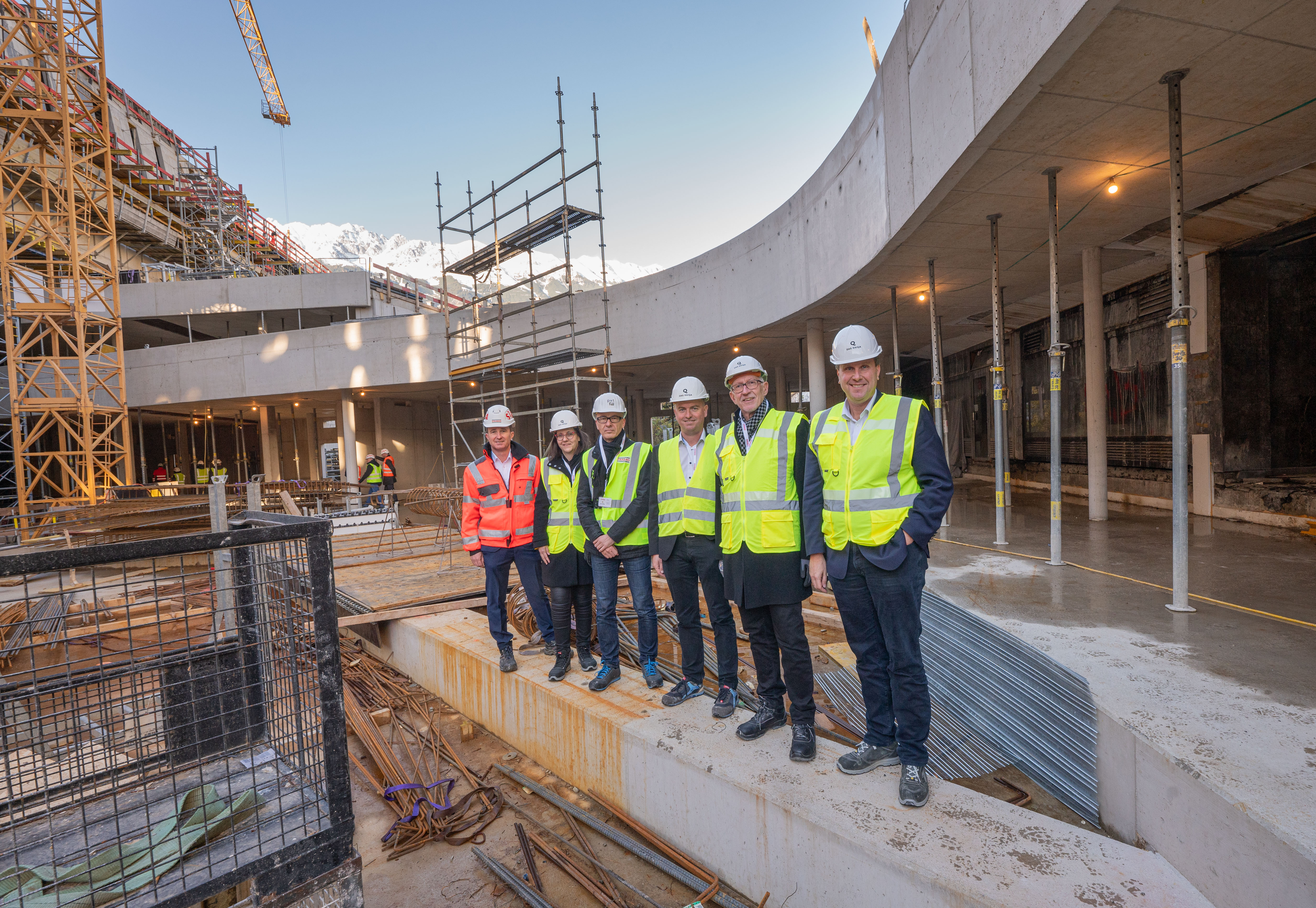 Foto von mehreren Personen mit Bauhelmen und Schutzwesten in einer Baustelle