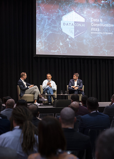 Foto von drei sitzenden Personen bei einer Podiumsdiskussion