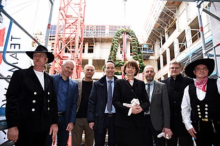 Foto mit der Oberbürgermeisterin von Köln auf der Baustelle im Antoniter Quartier in Köln. Um sie herum sind glück schauende Männer. 