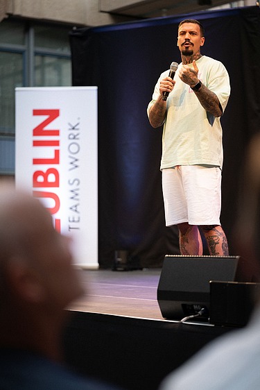 Foto von zwei Personen auf der Bühne. Sie spricht in ein Mikrophon.  