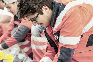Das Bild zeigt zwei Personen in Arbeitskleidung bei der Arbeit