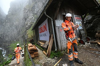 Foto von zwei Personen in Schutzuniform und Kletterausrüstung in einer Schlucht.    