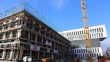 Foto vom Bau eines Hauses. An der Seite ist ein Karan zusehen. 