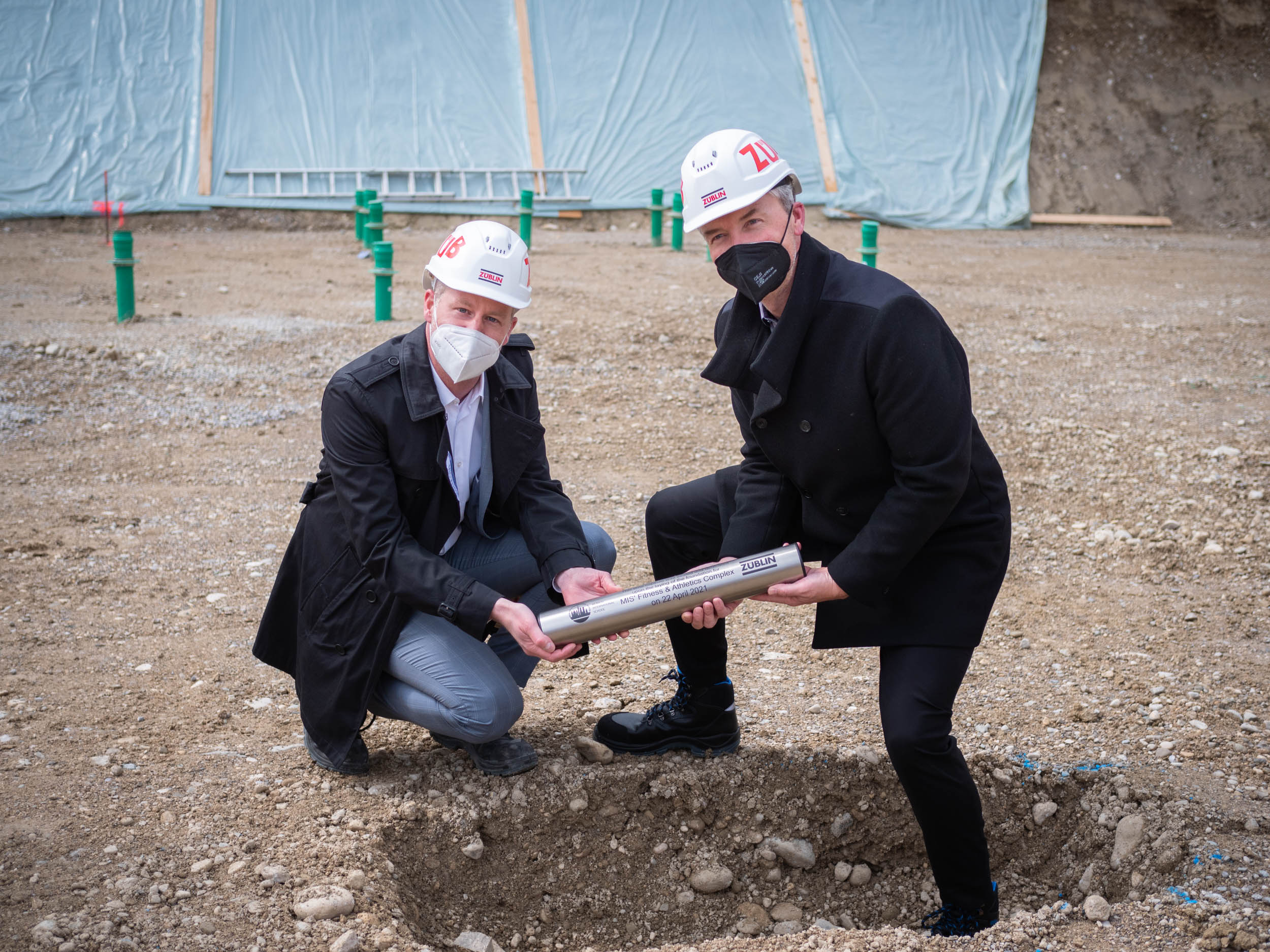 Foto von zwei Männern die eine Zeitkapsel vergraben.  