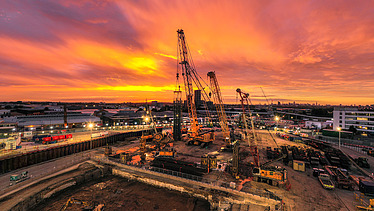 Baustelle mit Kränen bei Sonnenuntergang