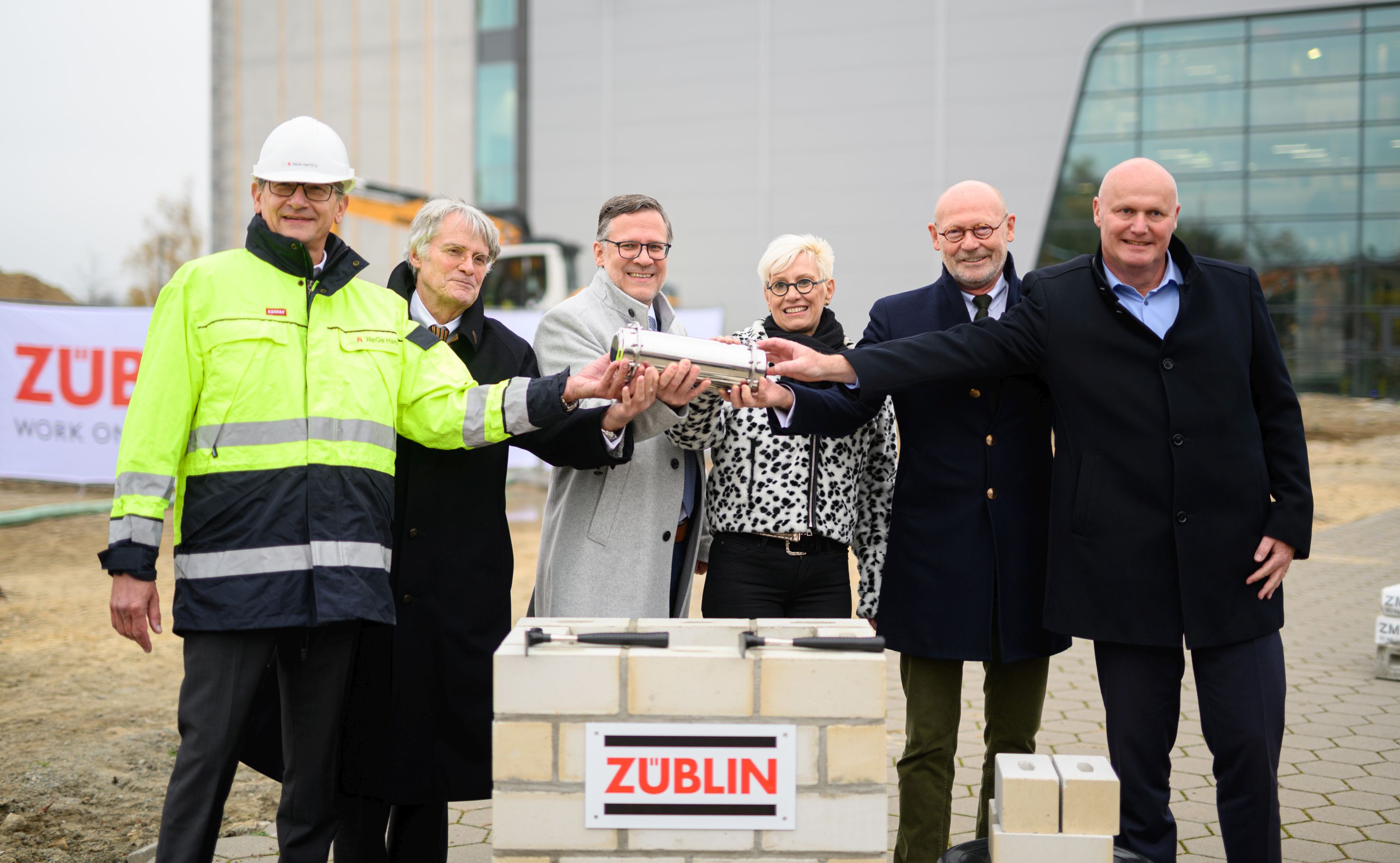 Foto von mehreren Personen, die eine Röhre halten zum Richtfest.  
