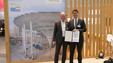 Zwei Männer mit Urkunde vorm ZÜBLIN-Forschungspreis Banner. 