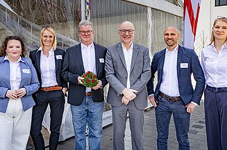 Elegant gekleidete Menschen stehen vor einem Zelt