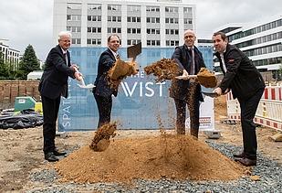 Foto von vier Männern, die mit einem Spatzen, Erde von einem Haufen Erde hochwerfen.  