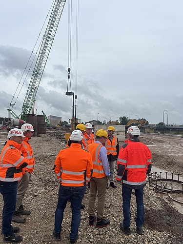Several people stand in safety clothing on a construction site