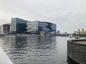 Foto von der „ODE“ in Amsterdam, mit Blick über einen Fluss.   