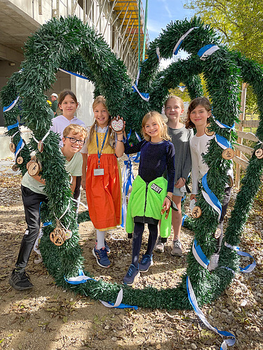 Foto von Schülerinnen und Schüler der Munich International School die den Richtkranz schmücken. 