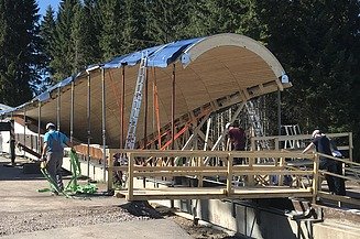 Foto von einer Baustelle im Wald, wo eine Überdachung aus Holz gebaut wird.      