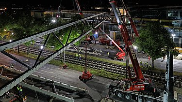 Foto von einer Brücke die grade gebaut wird aus der Vogelperspektive bei Nacht. 