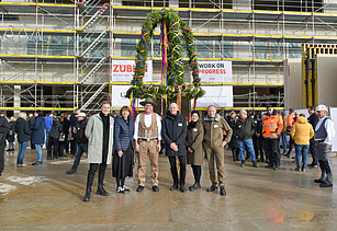 Foto von mehreren Personen vor dem Richtkranz von der Baustelle des Gymnasiums in Köln Deutz. 