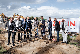 Das Bild zeigt Personen beim Spatenstich mit Schaufeln.