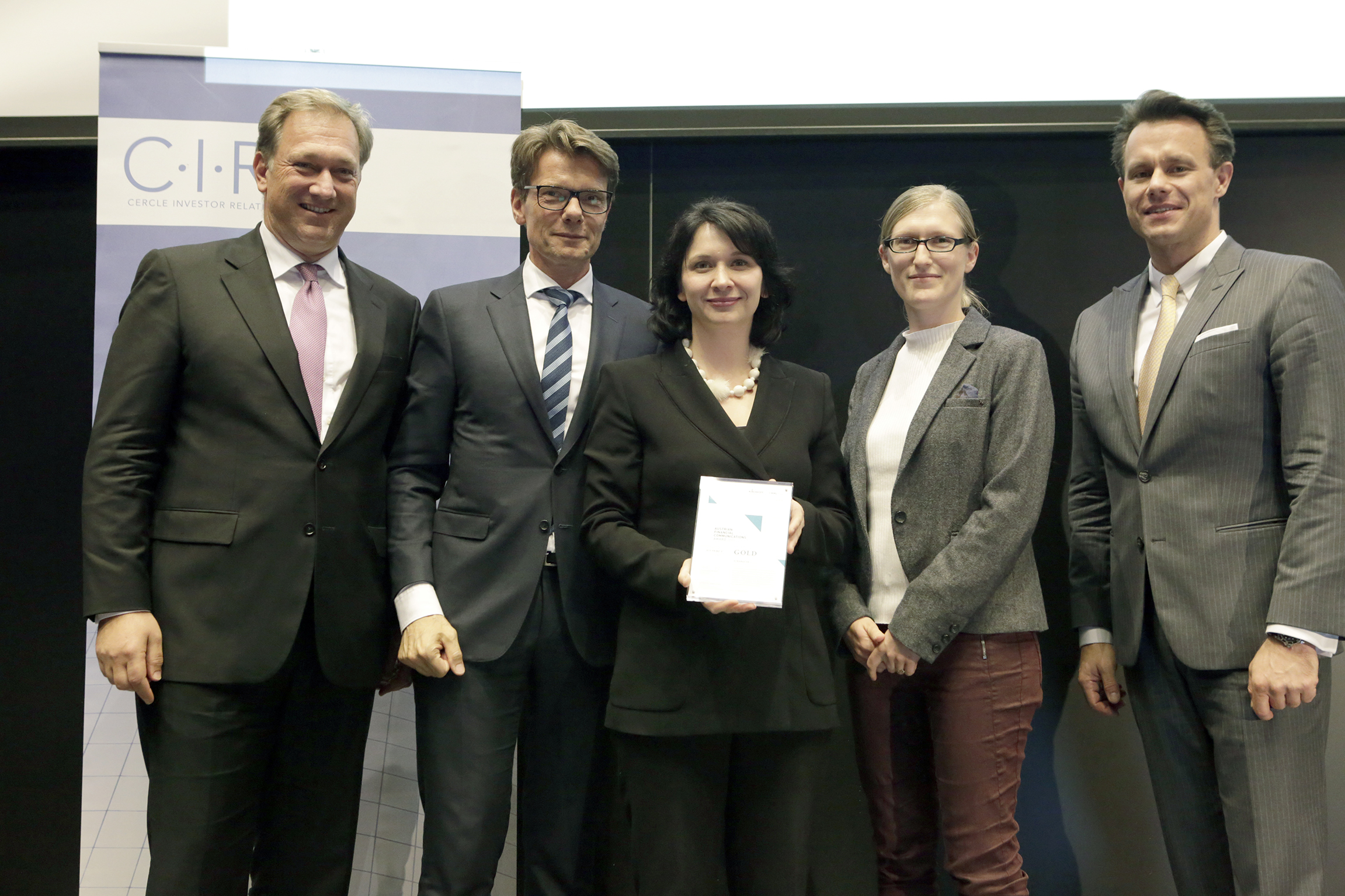 Photo of several people standing, the person in the middle holding a certificate