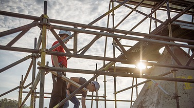  Foto von zwei Personen die auf einem Gerüst stehen.