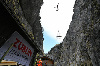 Foto von Hubschrauber, der Material in eine Schlucht abseilt.                 