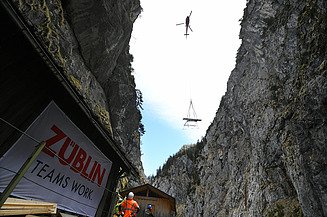 Foto von Hubschrauber, der Material in eine Schlucht abseilt.                 