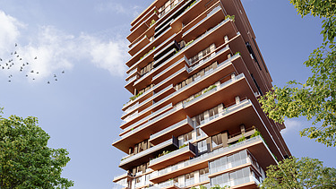 Foto zeigt einen Wohnbauturm mit Bäumen links und rechts